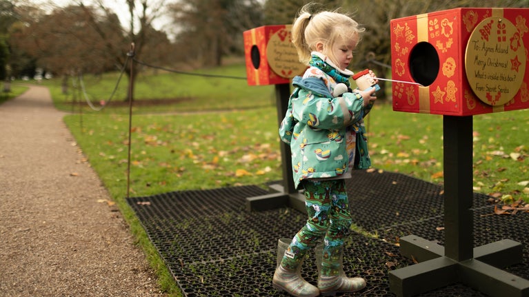 A child playing with peek boxes on an outdoor play trail at Killerton